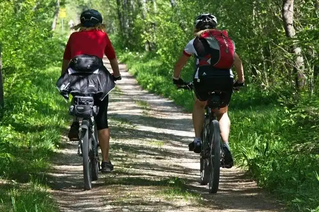 Vrouw en man mountainbiken door bospad
